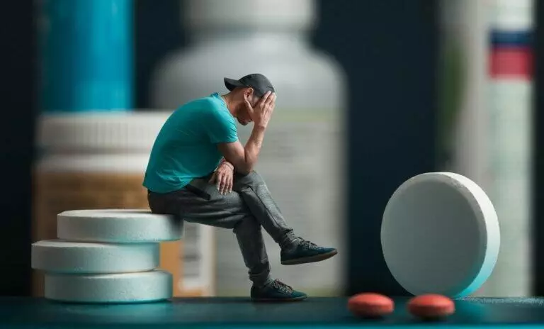 Image of depressed addicted man sitting on pills
