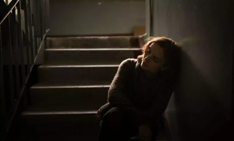 Sad, depressed woman sitting by the stairs