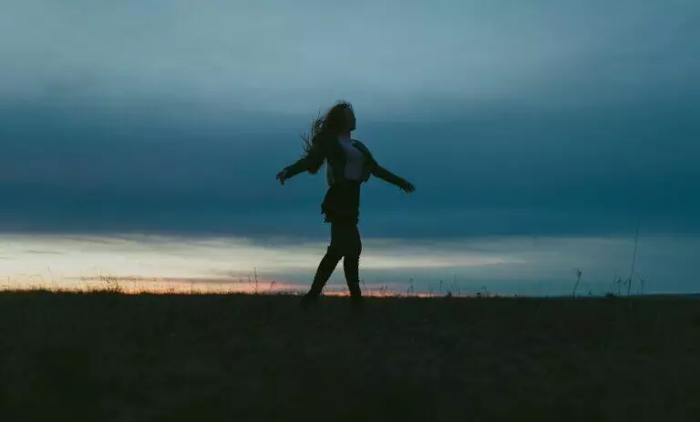 Silhouette of woman on a meadow at sunset