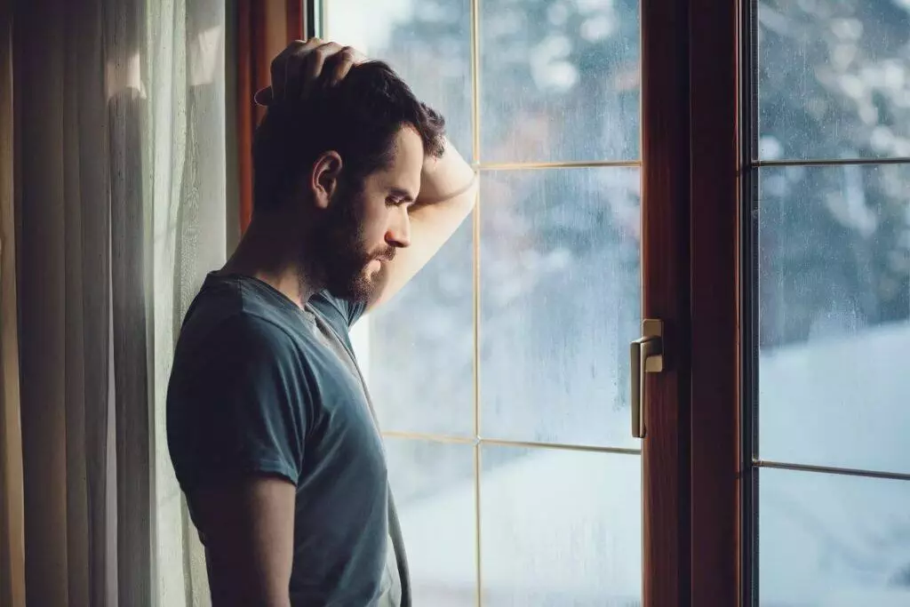 depressed regretful image of man standing by the window