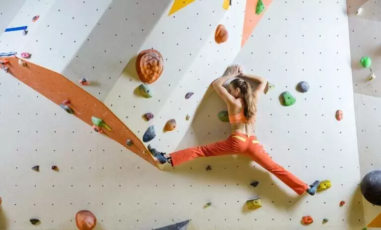 Young woman climbing challenging bouldering route. In climbing gym