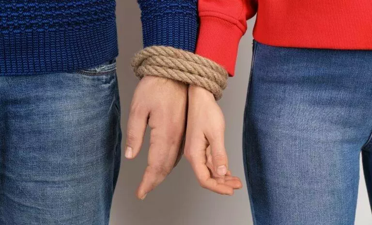 close up image of man and woman hands tied together