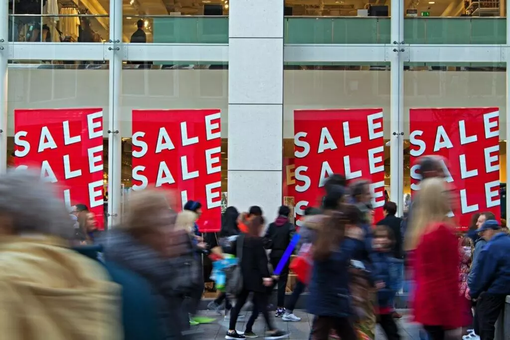 People out shopping with sale posters on mall windows