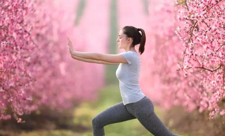 Woman doing tai chi exercise in a pink flowered field